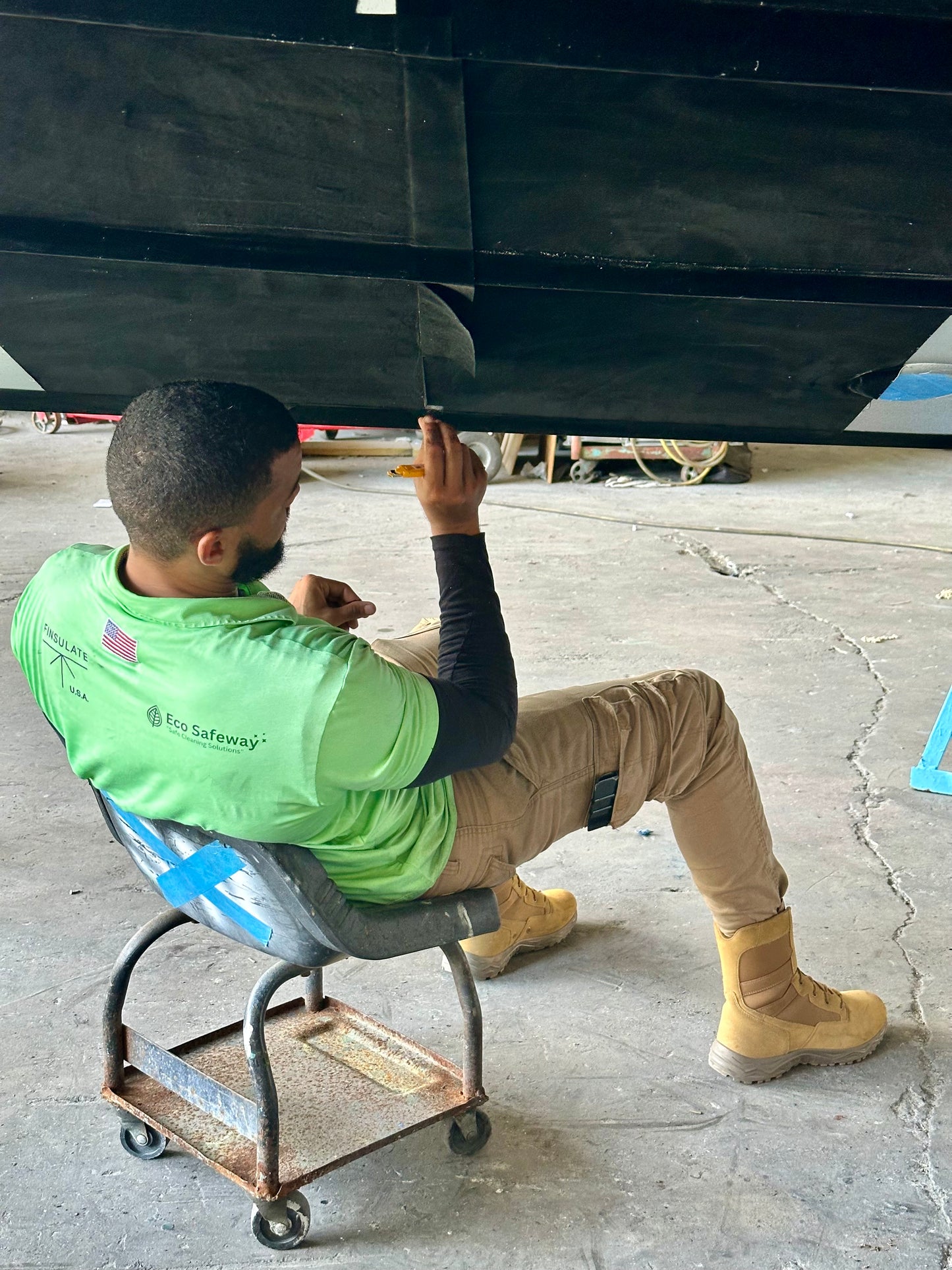 Person inspecting boat hull beneath with antifouling bottom paint alternative Finsulate Wrap.